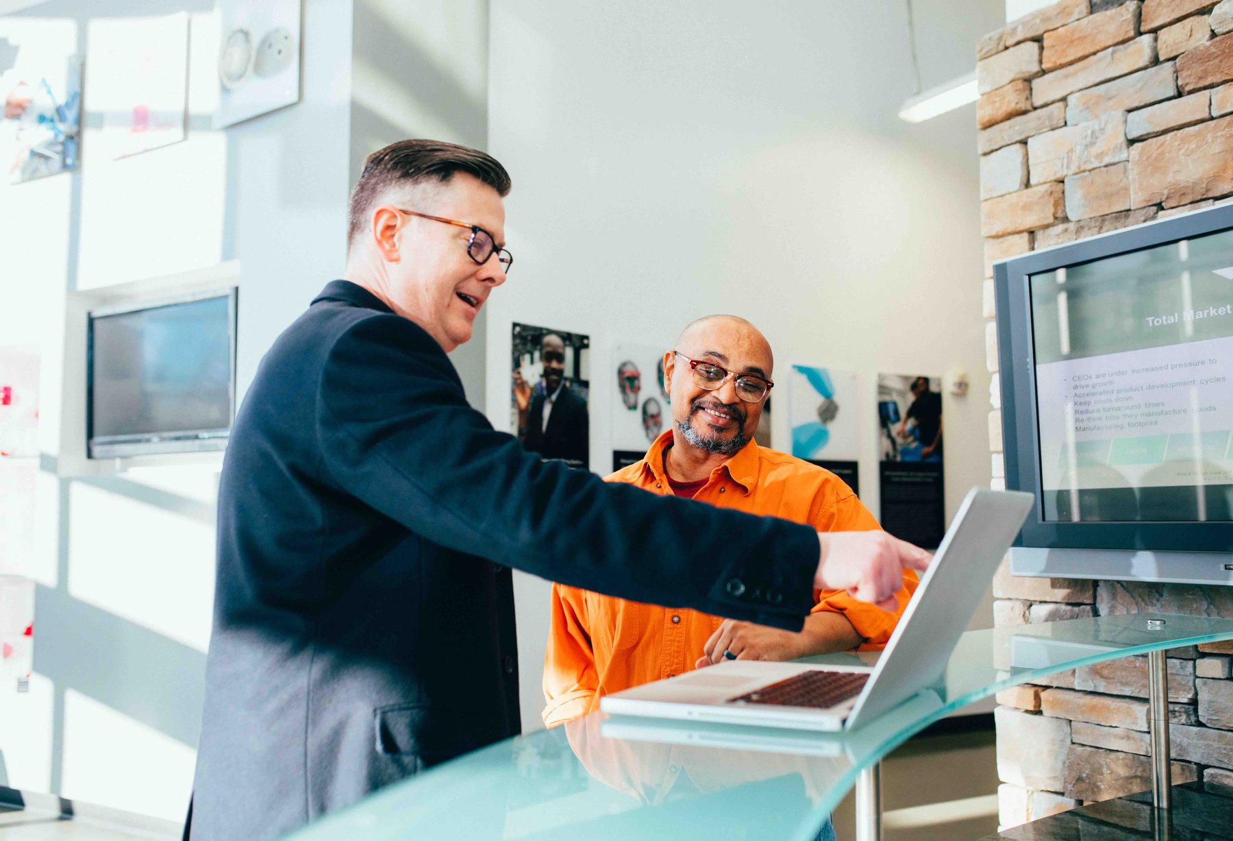 Two professionals reviewing data on a laptop in a corporate setting