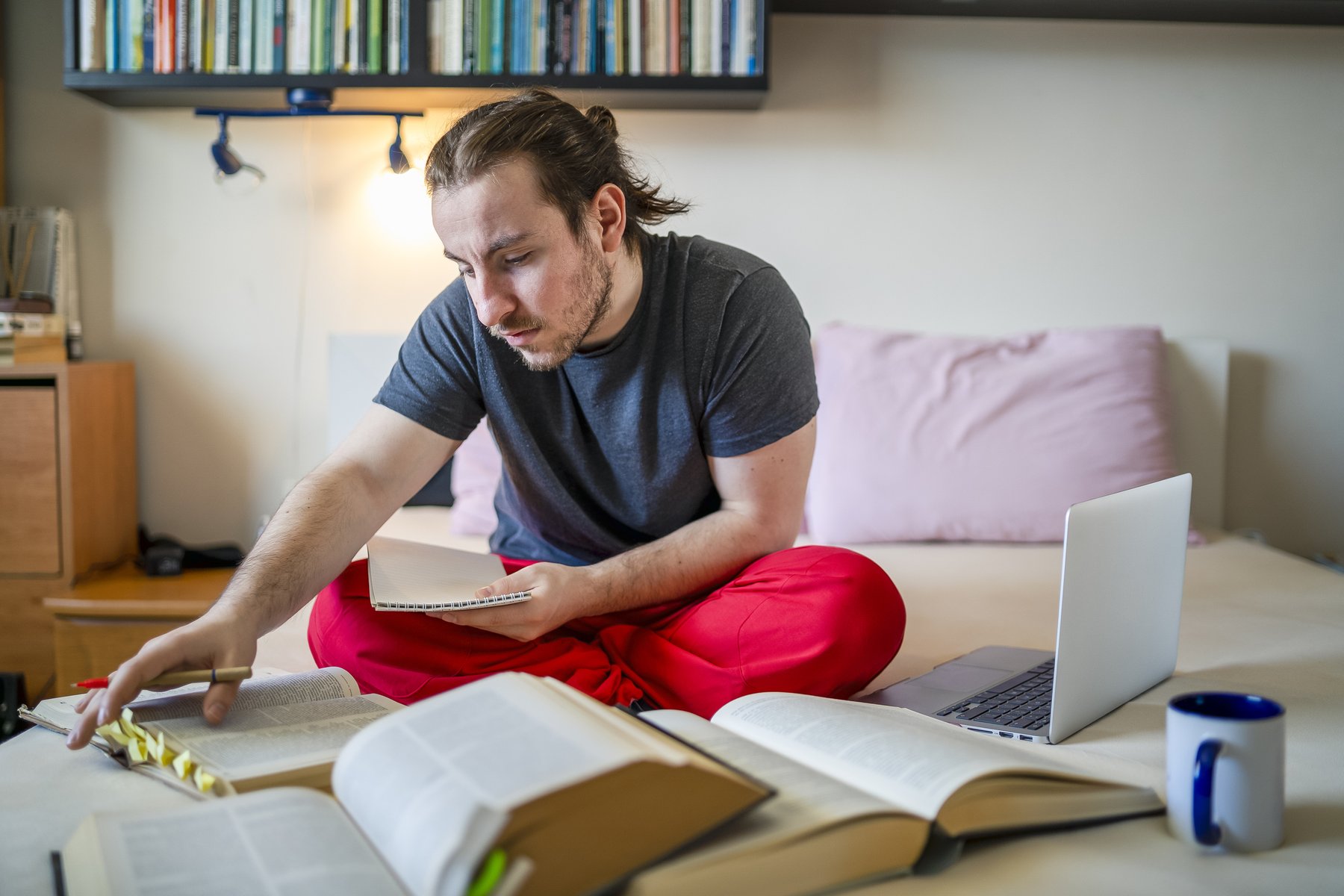 Student studying with books and laptop in shared housing